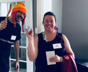 Lindsay posing with a strange item, David photobombs in a Jayne hat and holding a wooden cooking spoon.