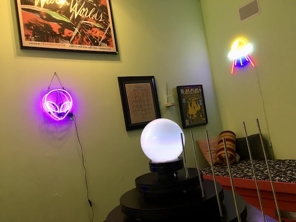 In-game: Paintings, alien neon lights, and a strange glowing orb atop a cone within the gift shop.