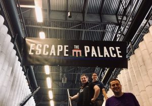 An "Escape the Palace" Banner hanginging over a stairwell with my team under it.