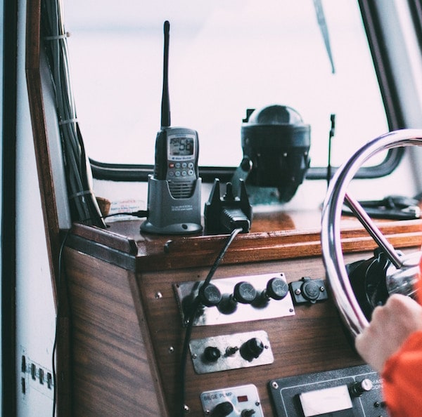 A walkie talkie in a cradle at the controls for a boat.