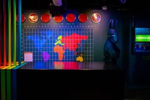 In-game: a character in a black rabbit costume standing before a multi-colored world map.