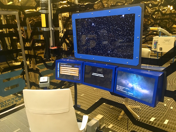 In-game: ship's helm with screens in front of it.