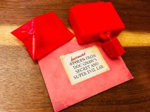 The red track, a locked box, a sealed envelope, and a ziplock bag with other mystery components.