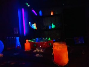 In-game: A dark laboratory with many jars and flasks filled with flourscing material.