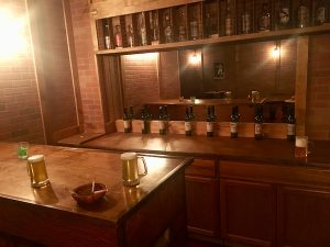 In-game: A bar with beers, a mixed drink, and an ashtray laying atop it.
