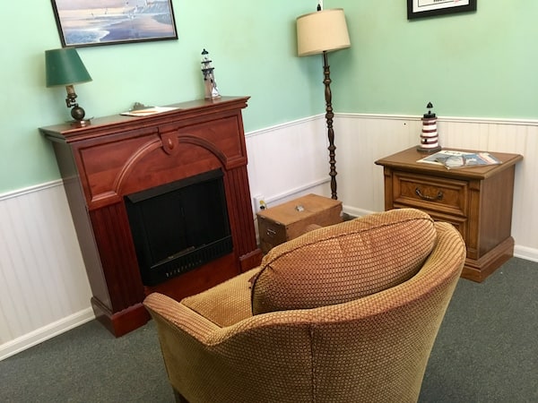 In-game: A quaint roob with a chair, fireplace, and lighthouse statues.