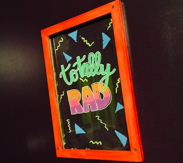 In-game: A dry erase board in pright pastel colors reads, "Totally RAD."