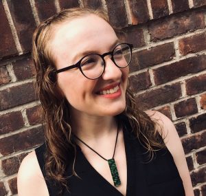 Lisa in front of a red bring wall.