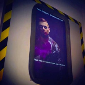 In-game: A test subject with dead eyes in a containment chamber.