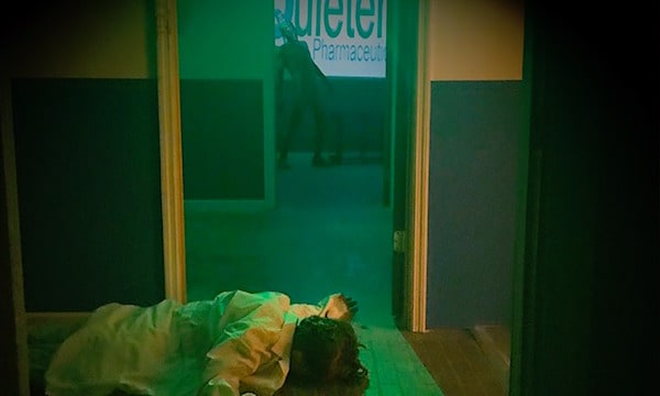 In-game: a dead body on the floor in the foreground, a zombie lurking in the background.