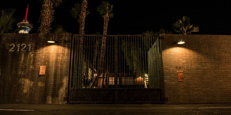 In-game: The front gates of the experience. a brick wall with an imposing black metal gate.
