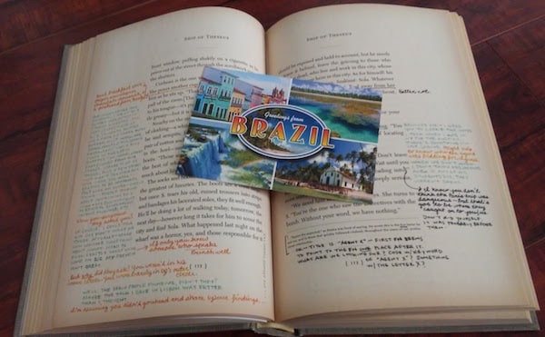 Sample pages of Ship of Theseus, along with a postcard that says "Greetings from Brazil."