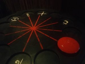 In-game: closeup of a puzzle with slots for many disks arranged in a circle.