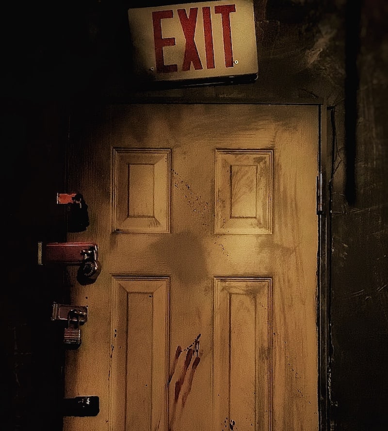 In-game: A door covered in padlocks with an exit sign above it.