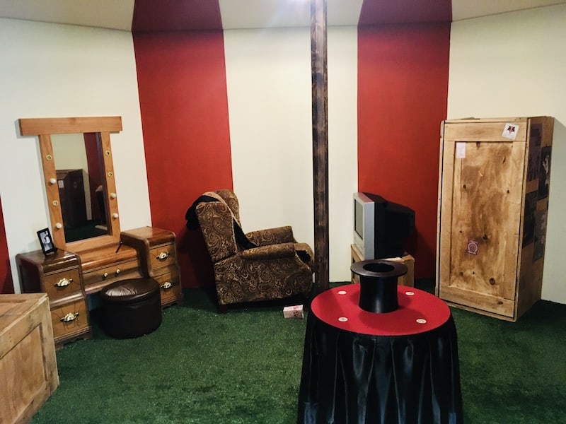 In-game: wide view of the citcus tent, a magician's hat on a table, crates lay about.