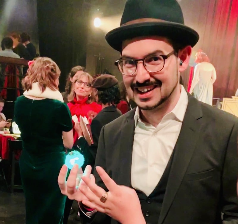 In-game: David in a suit holding a green glowing object and looking evil.