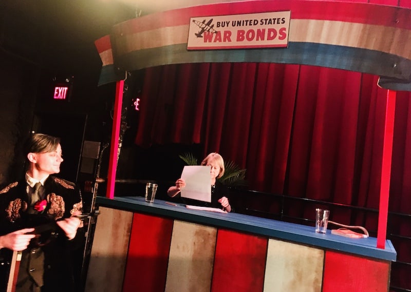 In-game: A woman sitting at a war bonds stand.