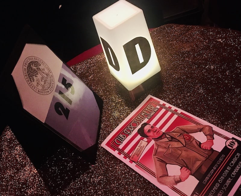 In-game: A table with an illuminated "D", a table number and a Club Drosselmeyer comic.
