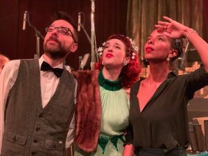 In-game: Two very good looking and brilliant puzzlers standing beside and actress as they all peer off into the distance.