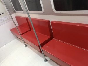In-game: Red bench seating in a train car. You can see a gold hinge running along the back of the seat.