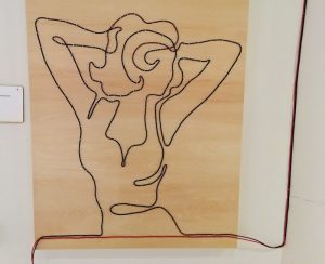 In-game: an image of a woman made out of wire mounted to a board.