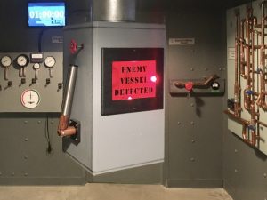 In-game: A periscope with a red illuminated sign that reads, "enemy vessel detected."