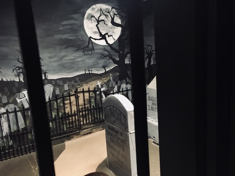 In-game: View of a a cemetary through a metal gate.