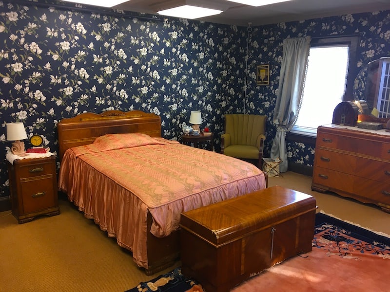 In-game: Wide view of an old bedroom centered on the bed.