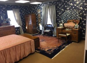 In-game: Wide view of a bed room with large dressers and a makeup vanity.