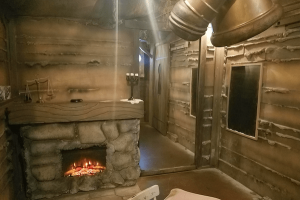 A large mirror hangs between a fireplace and a chalkboard in a rustic den.