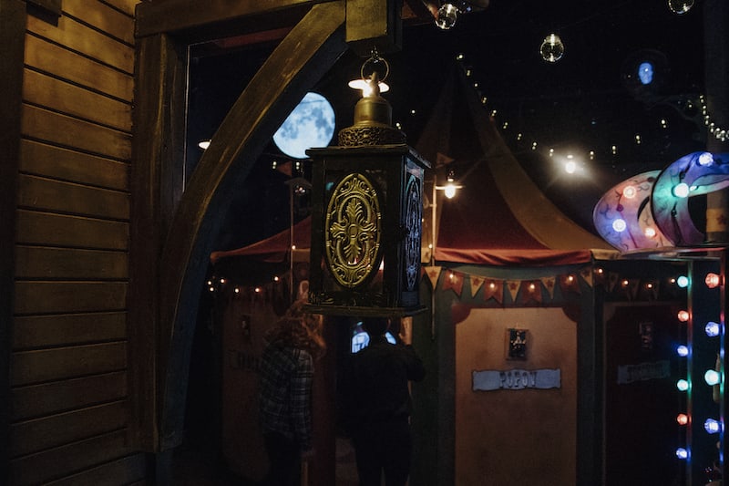 In-game: The citcus exterior with a large tent illuminated in the moonlight.