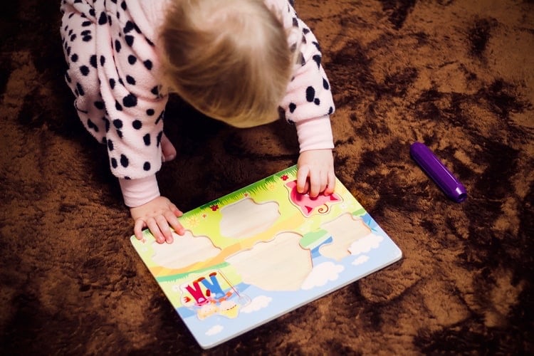 A toddler attempting to assemble a simple puzzle.