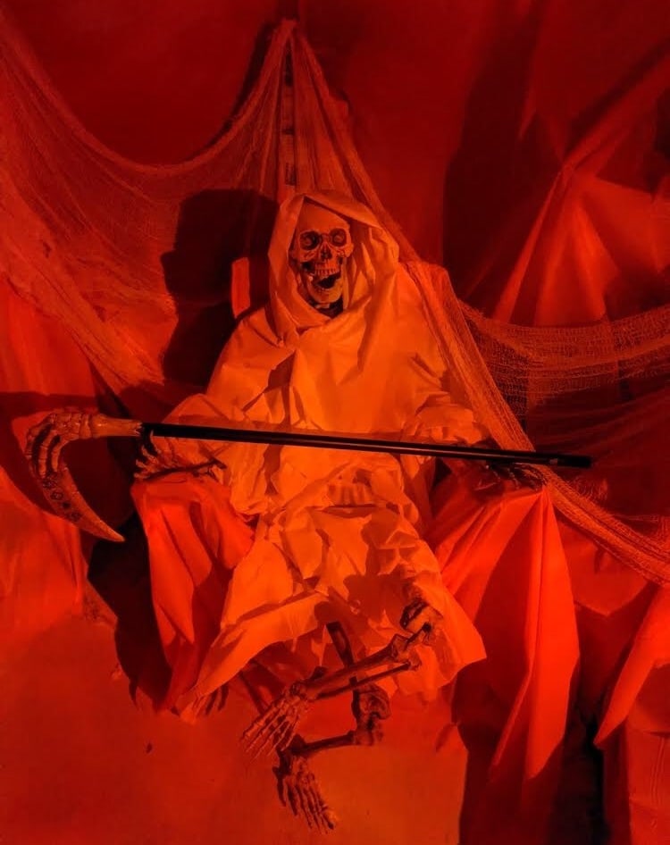 A white cloaked skeleton holding a scythe.