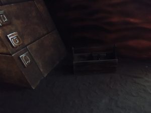 In-game: A wooden toolbox sitting in the sand beside the base of an ancient pyramid.