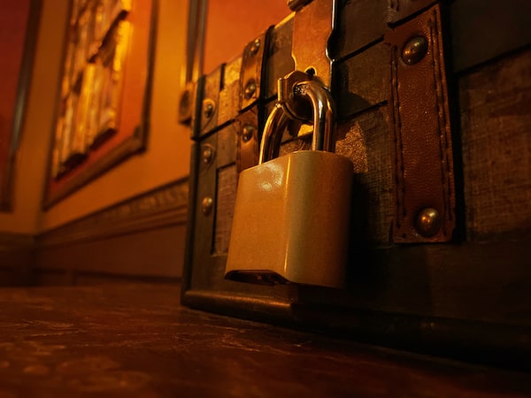 Close-up of a trunk on the floor, padlocked shut.