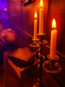Close-up of a lit candelabra with books and a globe visible in the background.