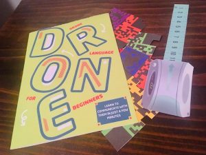 Drone Language for Beginners guide, beside a few paper cut items.