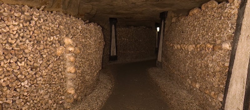 A tunning within the Catacombs of Paris. The walls are linked with human bones. 