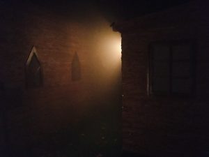 In-game: The space between a house and a neighboring church at night.