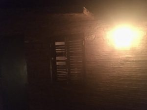 In-game: The side of an old, rundown home at night.