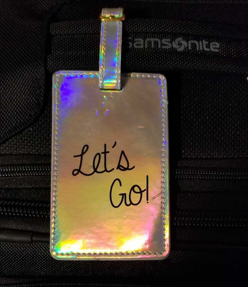 Closeup on a luggage tag that reads, "Let's Go!"