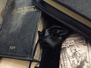 Closeup of the box contents includes a Holy Bible, newspaper clippings, and other items.
