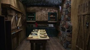 A photo of the room. There's a table set for 7 in a cabin's kitchen.