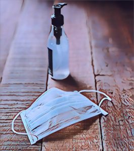 A mask and a bottle of hand sanitizer on a wooden table.