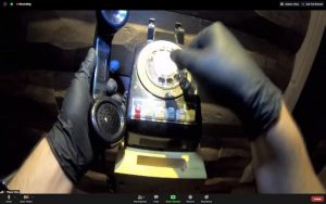 A pair of hands in black latex gloves manipulating an old rotary phone.