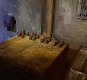 An unusual wooden box covered in metal sockets.