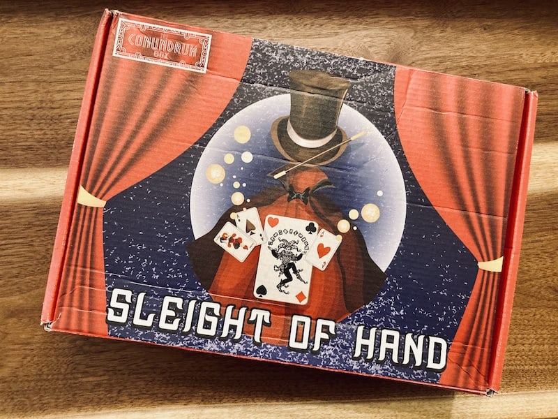 Box art for Sleight of Hand, depicting an empty magician's cape with a floating hat, wand, and cards as if an invisible spirit were holding them.