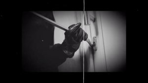 Image of a gloved hand using a crowbar on a door.
