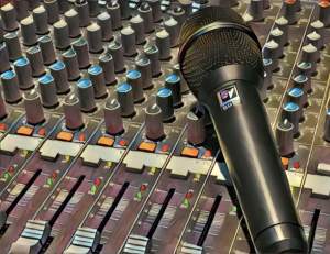A microhone resting on a mixing board.