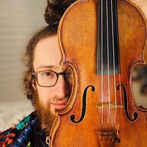 Matthew with half his face covered by his violin.